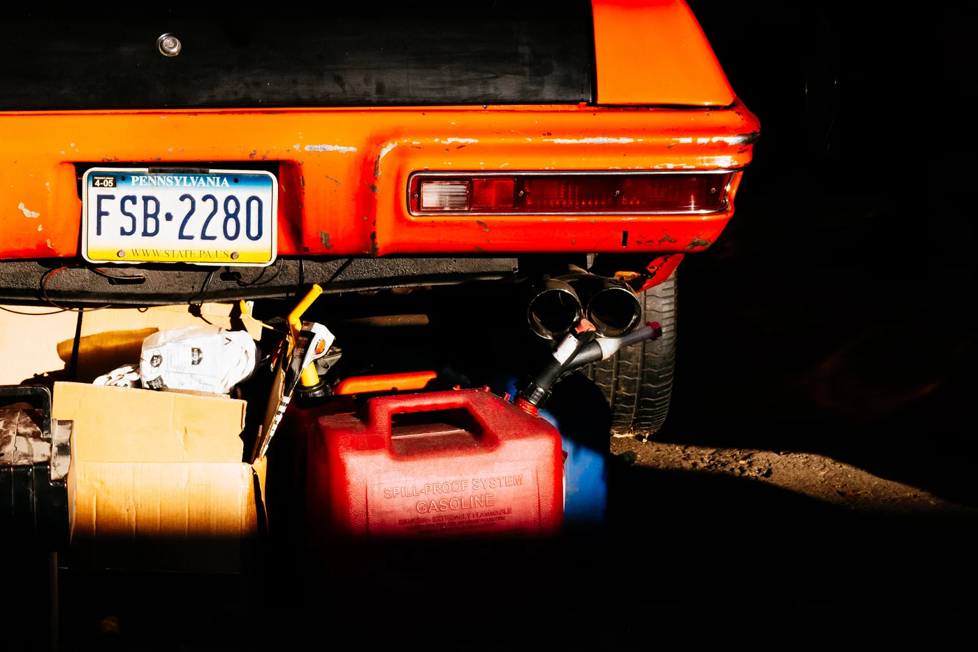 orange sports car with gas can against a dark background.